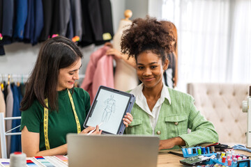 Portrait of young african american woman and young girl fashion designer stylish sitting and working with color samples.Attractive two designer girl work with colorful fabrics at fashion studio