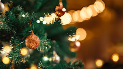 Christmas holiday background. Gold bauble ball hanging from a decorated on Christmas tree with...