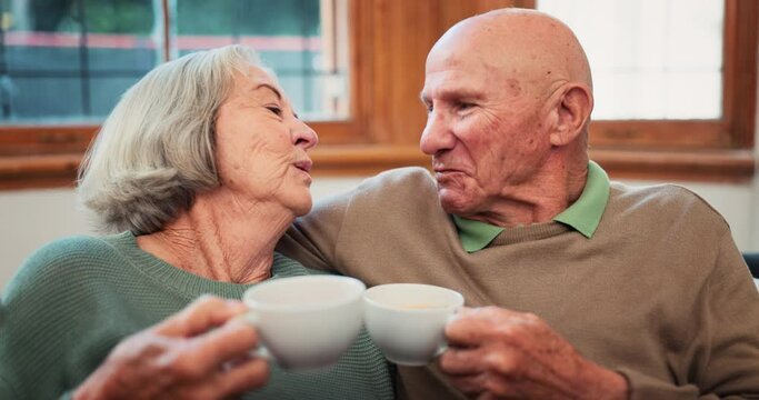 Old couple, tea and love care in retirement home for cheers connection, pensioner together or morning kiss. Man, woman or hot drink on sofa for celebration or marriage calm, communication or happy