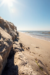Sunny beach sky at midday in summer. Calm Baltic Sea. A mountain of sand blown by the waves. The low-angle photo was taken with a wide-angle lens