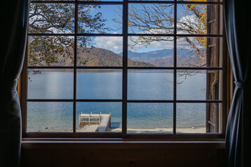 窓の向こうに見える紅葉した湖畔の景色