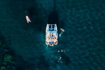 Amazing top view of Catamaran anchored in blue sea in summer. Travel background. Cruise vacation.