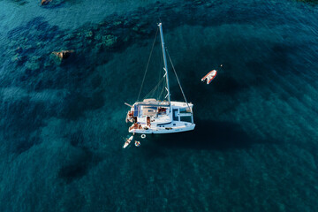 Amazing top view of Catamaran anchored in blue sea in summer. Travel background. Cruise vacation.
