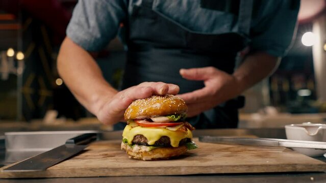 Close-up of a chef pinning a burger with beef patty with vegetables and cheese cooked in the professional kitchen of an Italian restaurant
