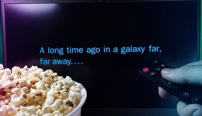 Fototapeta premium Kyiv. Ukraine. 10.11.2023: Person watching Star Wars movie with popcorn and remote control. A long time ago in a galaxy far, far away. Stock editorial photo.