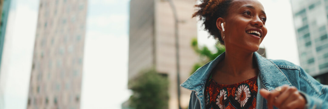 Closeup, Smiling African Girl With Ponytail Wearing Denim Jacket, In Crop Top With National Pattern Listening To Music On Headphones And Dancing Outdoors.