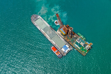 Sand dredger on floating platforms in ocean.