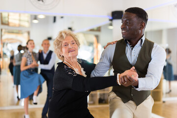 Woman pensioner with african man practising charleston