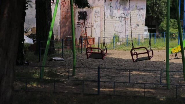 Children's red swings, close-up. empty children's swing in the playground. Empty playground in the park with swings. Children's swing with a seat suspended on chains. red swings.