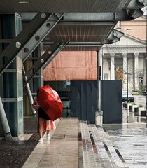 Ragazza con ombrello rosso sotto la pioggia che passeggia