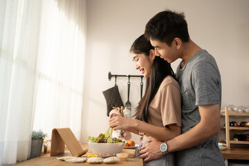 Love, romance and fun Asian couple hugging, cooking in a kitchen and sharing an intimate moment....