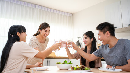 Happy Asian friends lunching with healthy food home- Young people having fun eating meal and drinking water for lunch.