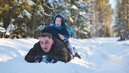 Fototapeta na wymiar A father and his young son playing in the winter woods.
