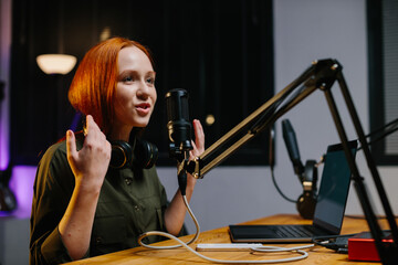 The girl radio presenter speaks into the microphone during the broadcast at the radio station....