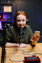The girl in headphones speaks into the microphone while holding the phone in her hands. The concept...