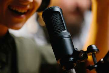 Close-up, dubbing actor or radio host speaking into a microphone.