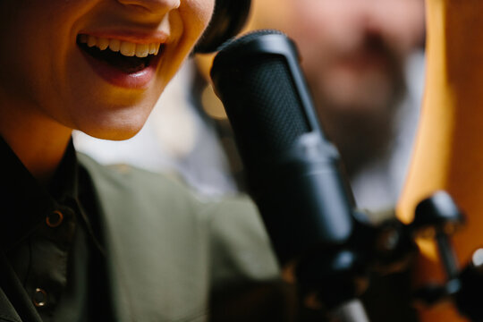 Close-up, dubbing actor or radio host speaking into a microphone.