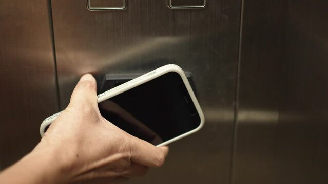 Hand of woman using smart phone to unlock for use elevator in the hotel. Digital or keyless to authenticate.