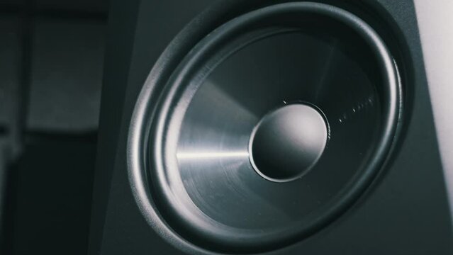 Studio bass speaker vibrates from loud music in a recording studio, close-up. Modern loudspeaker membrane pumping from bass sound in slow motion. Working bass cone on low frequency. Hi-fi sound system