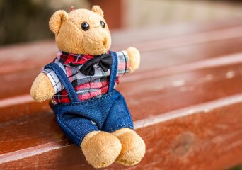 Bear toy with bow tie on a wooden bench