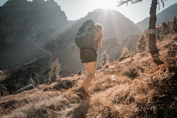 Bergsteigerin geht in den Alpen mit Rucksack bergauf, Herbstlandschaft in den Bergen