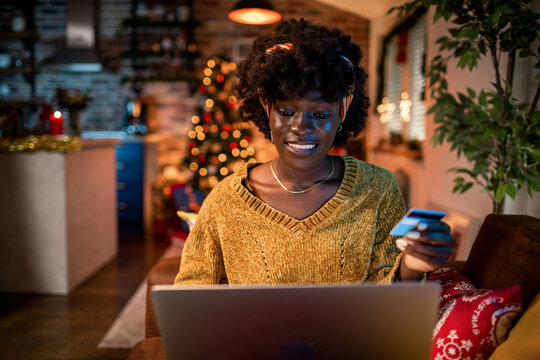 Young woman holding credit card with laptop at home. Online shopping at Christmas holidays.
