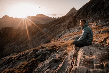 Photo sur Plexiglas Dolomites Bergsteiger in Daunenjacke schaut in den Sonnenuntergang in den italienischen Bergen am Comer See, Bicacco Ledu