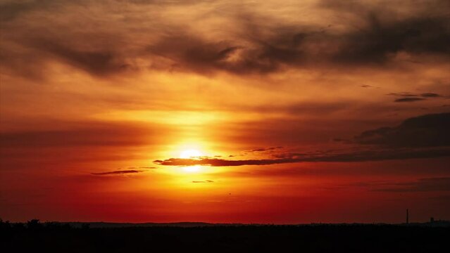 Amazing sunset in orange sky with soft clouds, Timelapse. 4K. Bright sun setting down above the horizon. Dramatic colorful dark sunset epic clouds. Vibrant color. Time-lapse. Sundown, Cloudscape