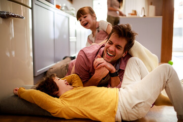 Happy loving father playing with kids in living room