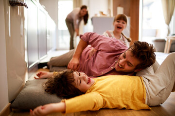 Happy loving father playing with kids in living room