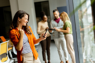 Young business woman with mobile phone in front of her team at the office