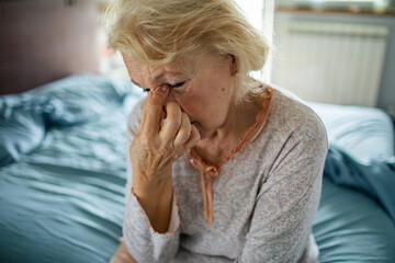 Worried Senior Woman Sitting in Bed