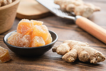 Candied ginger pieces and ginger roots on wooden kitchen table. Healthy sweets.