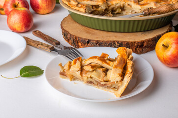 a slice of apple pie on a plate, ready to eat. Thanksgiving traditional dessert with red and green apples, Thanksgiving tart preparation, autumn bakery. Food lifestyle, recipe