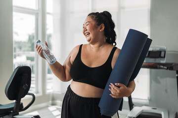 Plus size Asian woman exercises in gym. Beautiful overweight woman in sportswear smiling and happy in fitness. concept of body positive, self-acceptance, weight loss. - obrazy, fototapety, plakaty
