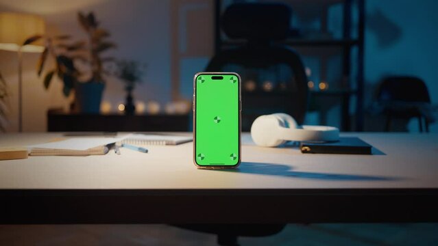 Smartphone with blank green screen on table in homeoffice