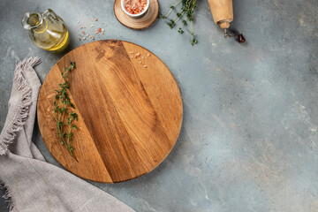 Round wooden board plate with herbs and salt on a light background top view. copy space