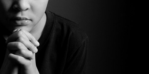 boy praying to God with hands held together with closed eyes on grey background stock photo	