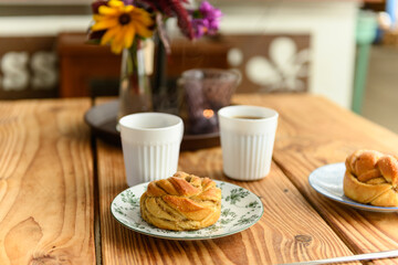 Delicious cardamom buns and coffee on table in cafe