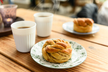 Delicious cardamom buns and coffee on table in cafe