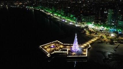 Aerial shot of the Marco dos Corais in Brazil with an illuminated Christmas tree in the night - obrazy, fototapety, plakaty