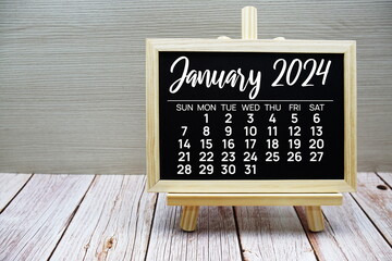 January 2024 monthly calendar on easel stand on wooden background