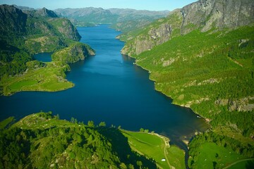 Naklejka na ściany i meble Bird's eye view of fjord surrounded by green vegetation in Norway