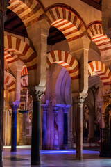 Arches and columns inside the cathedral mosque of Córdoba, with an entrance of natural light that contrasts with the artificial lighting.