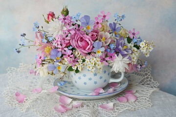 Bouquet of spring and summer flowers in a cup on the table, roses, aquilegia, spirea, forget me not flowers, pansies, violet, beautiful postcard, still life, blur. - 677247395