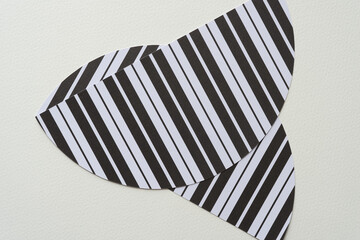 two striped paper shapes (semi circles) with black and white stripes on blank paper