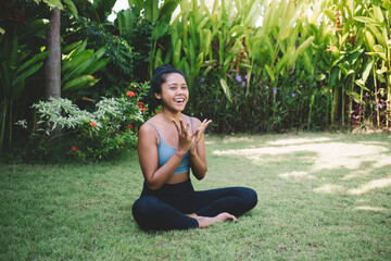 Cheerful ethnic woman showing sign and sitting in lotus pose