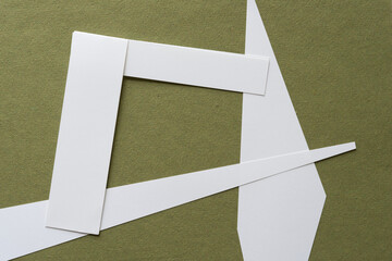squaring frame composed of various cut paper shapes on rough green paper