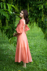 Obraz na płótnie Canvas Profile portrait of a beautiful brunette girl in dress posing in the park, tree background. 