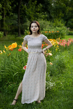Full length image of a beautiful brunette girl in dress posing in the park, tree background.
